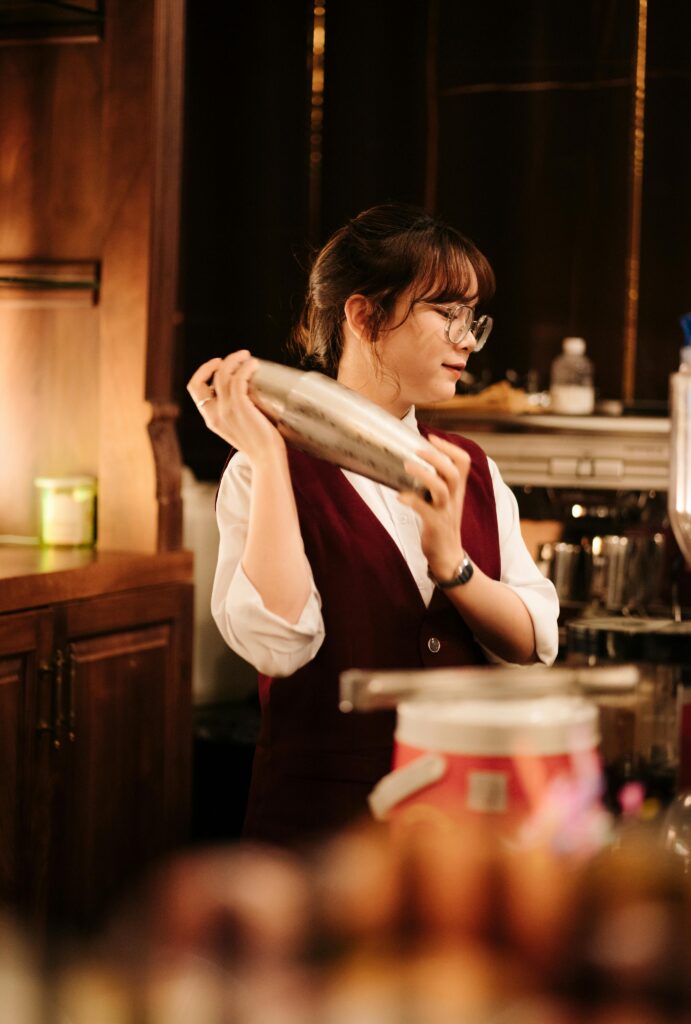 Female bartender in a chic bar shaking a cocktail with elegance and skill.