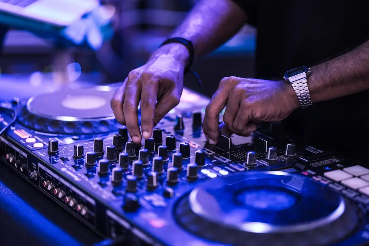 DJ skillfully mixes tracks on a controller with vibrant lighting.